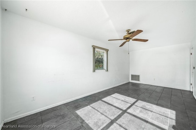 unfurnished room with ceiling fan and dark tile patterned floors