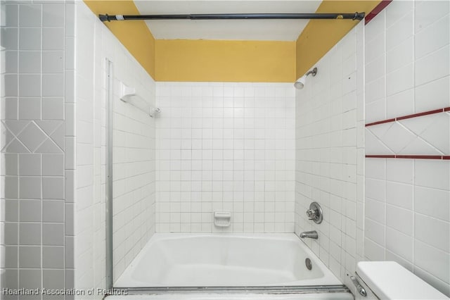 bathroom with toilet and tiled shower / bath