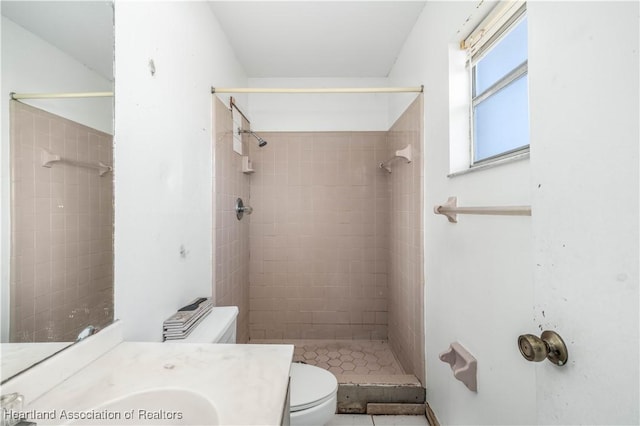 bathroom with tiled shower, vanity, and toilet