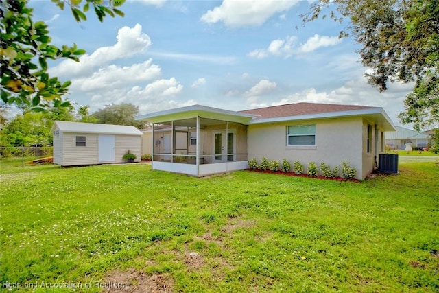 rear view of property with a lawn, central AC, and a shed