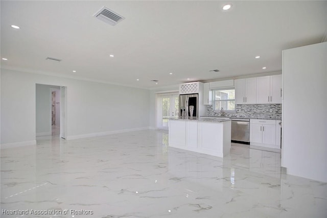 kitchen featuring a center island, white cabinets, ornamental molding, appliances with stainless steel finishes, and tasteful backsplash