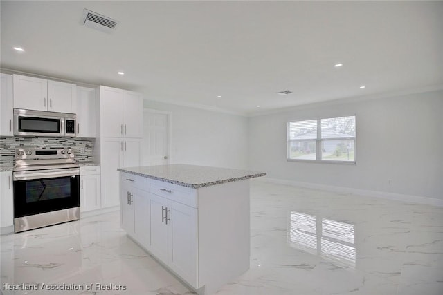 kitchen with white cabinets, crown molding, stainless steel appliances, and tasteful backsplash