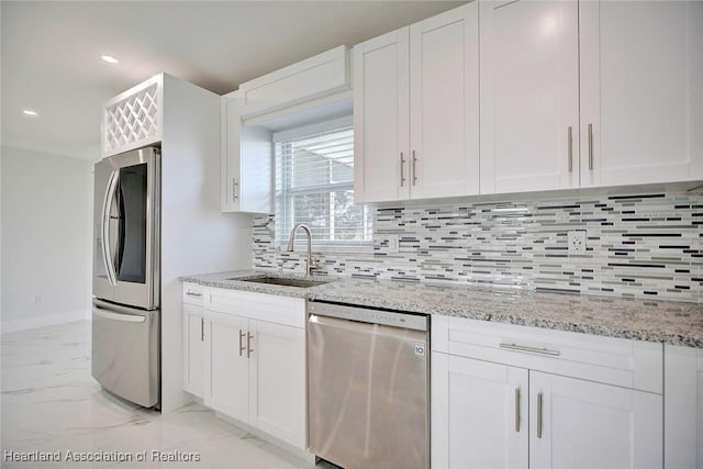 kitchen featuring light stone countertops, stainless steel appliances, white cabinetry, and sink