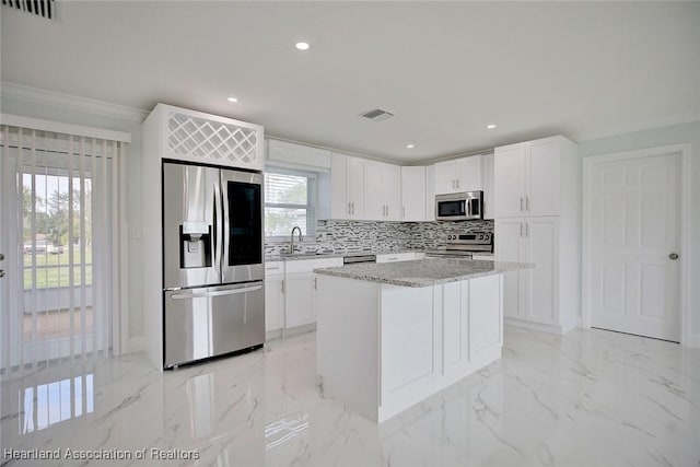 kitchen featuring a center island, sink, light stone counters, white cabinetry, and stainless steel appliances