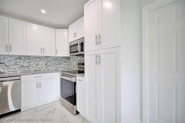 kitchen featuring tasteful backsplash, white cabinetry, stainless steel appliances, and light stone counters