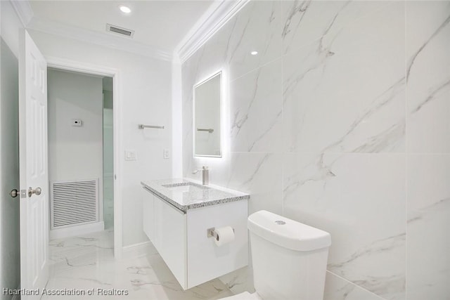 bathroom featuring vanity, toilet, ornamental molding, and tile walls