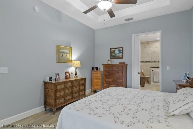 bedroom with ceiling fan, a tray ceiling, and light wood-type flooring