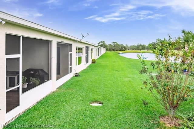 view of yard with a sunroom and a water view