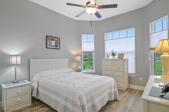 bedroom with multiple windows, ceiling fan, and light hardwood / wood-style floors