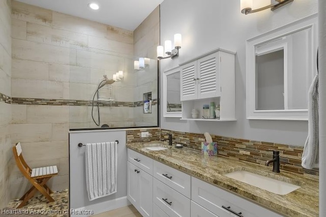 bathroom with vanity, a tile shower, and backsplash