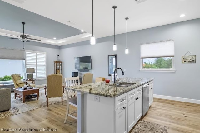 kitchen with dishwasher, a kitchen island with sink, white cabinetry, light stone countertops, and decorative light fixtures