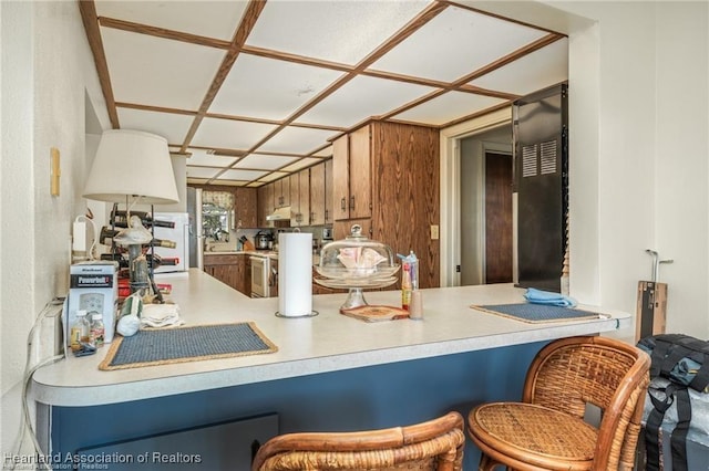 kitchen with white range with electric cooktop, kitchen peninsula, and a breakfast bar