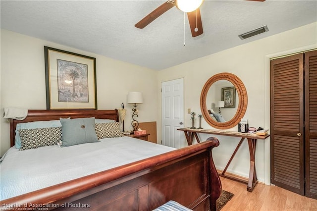 bedroom featuring ceiling fan, a closet, a textured ceiling, and light wood-type flooring