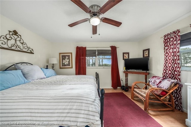 bedroom with hardwood / wood-style flooring, ceiling fan, and multiple windows