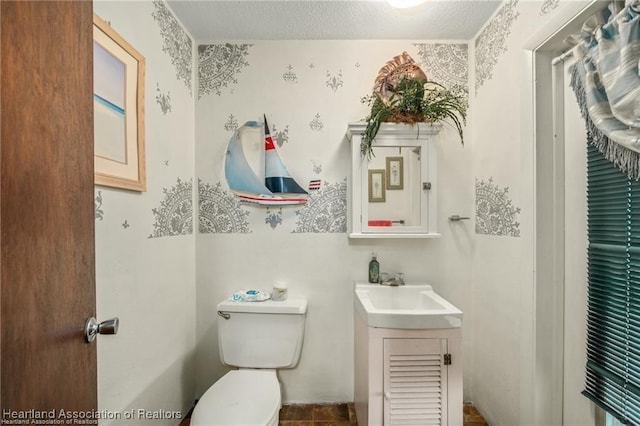 bathroom featuring vanity, a textured ceiling, and toilet