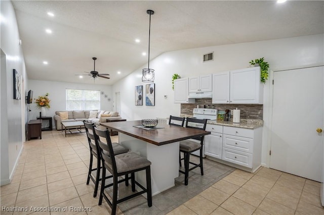 kitchen with decorative backsplash, light tile patterned floors, white cabinets, and lofted ceiling