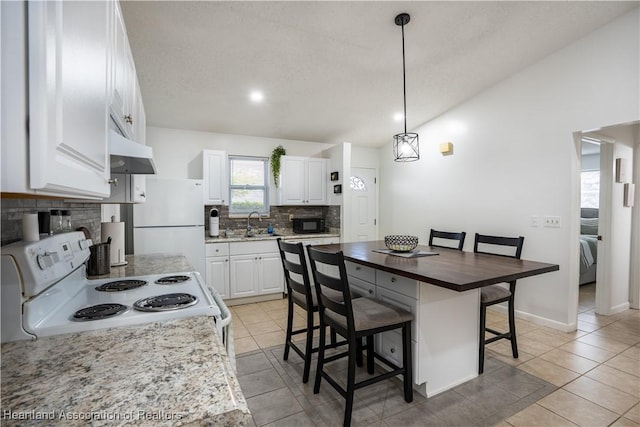 kitchen with white appliances, white cabinets, a kitchen island, decorative light fixtures, and butcher block countertops