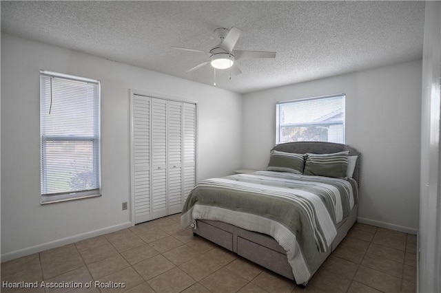 bedroom with ceiling fan, light tile patterned floors, a closet, and a textured ceiling