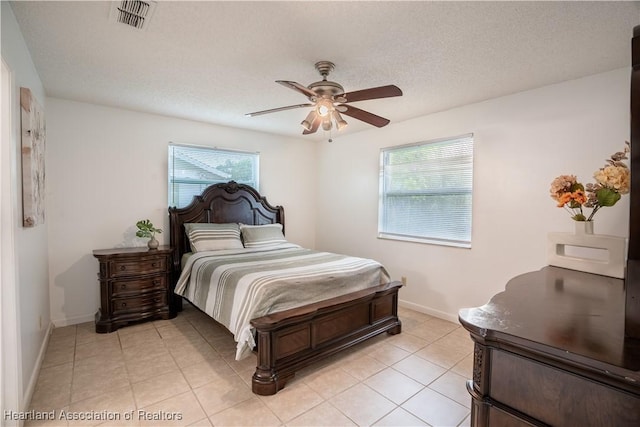 tiled bedroom with ceiling fan, multiple windows, and a textured ceiling