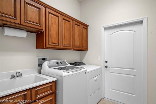 washroom featuring cabinet space, washing machine and dryer, and a sink