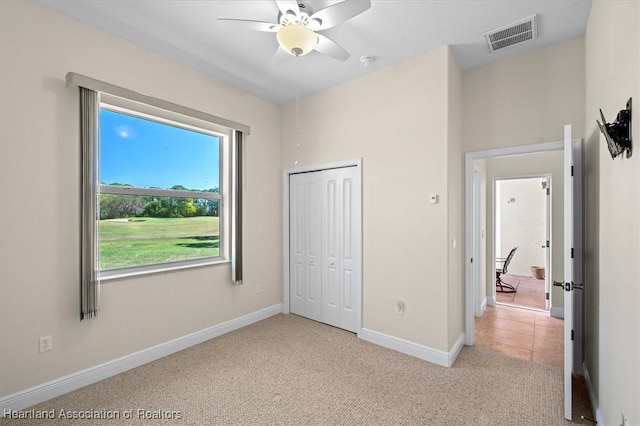 bedroom with a closet, light carpet, baseboards, visible vents, and ceiling fan