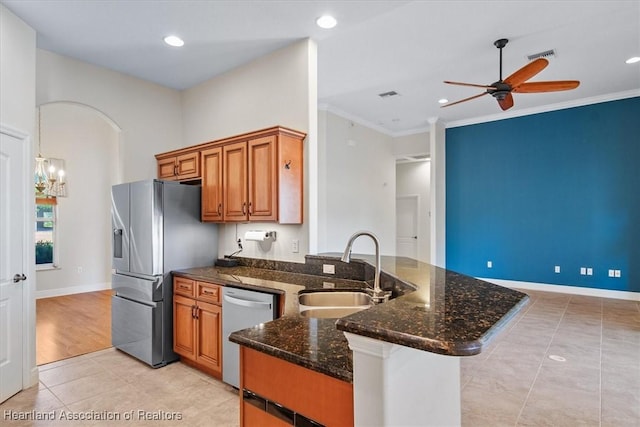 kitchen with stainless steel appliances, a sink, ceiling fan, a peninsula, and brown cabinetry