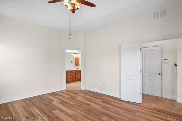 empty room featuring light wood-type flooring, a ceiling fan, baseboards, and visible vents