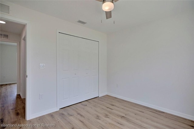 unfurnished bedroom featuring ceiling fan, a closet, and light wood-type flooring