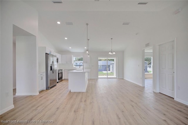 kitchen with white cabinets, light wood-type flooring, stainless steel appliances, and hanging light fixtures