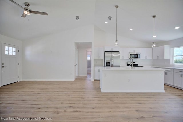 kitchen with a kitchen island with sink, white cabinets, hanging light fixtures, and appliances with stainless steel finishes