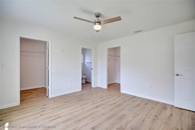 unfurnished bedroom featuring ensuite bathroom, ceiling fan, light wood-type flooring, and a spacious closet