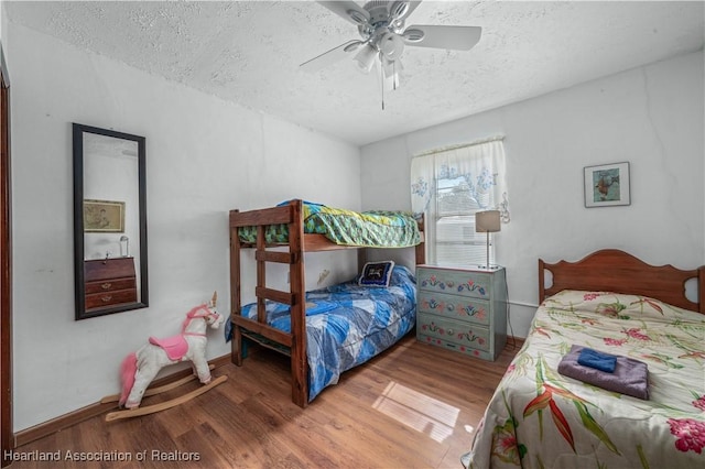 bedroom with ceiling fan, hardwood / wood-style flooring, and a textured ceiling