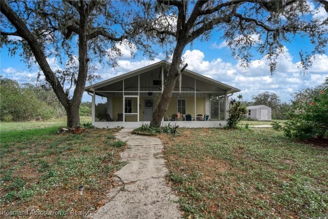 view of front of property featuring a front yard, a sunroom, and a storage unit