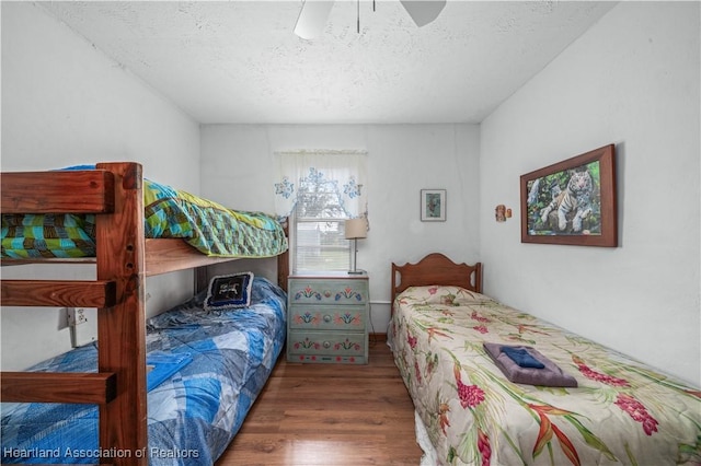 bedroom with ceiling fan, dark hardwood / wood-style floors, and a textured ceiling