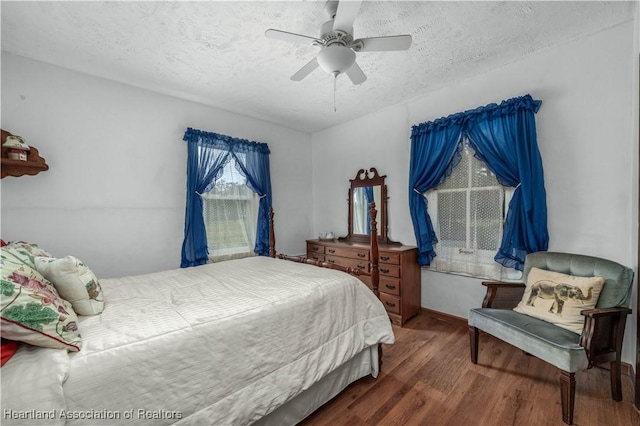 bedroom featuring ceiling fan, dark wood-type flooring, and a textured ceiling