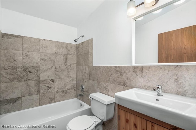 full bathroom with vanity, toilet, tiled shower / bath combo, and tile walls