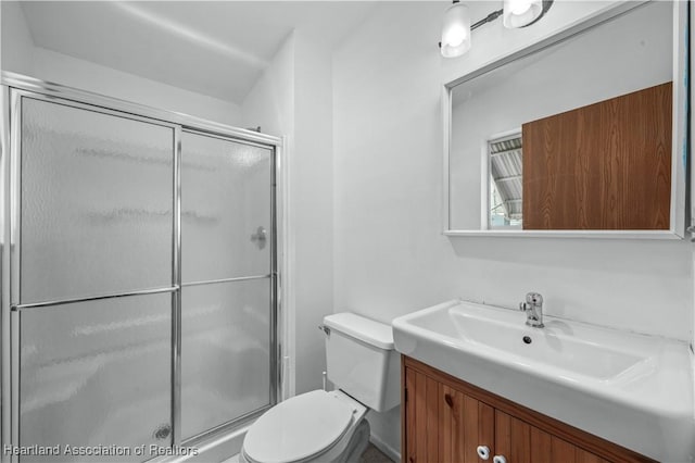 bathroom featuring vanity, a shower with shower door, and toilet