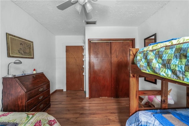 bedroom featuring dark hardwood / wood-style flooring, ceiling fan, a closet, and a textured ceiling