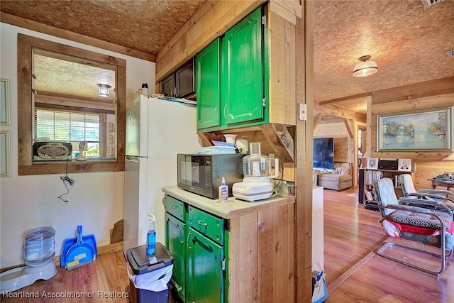 1320 Lakeview Dr, Sebring, FL 33870 - kitchen with black microwave, green cabinetry, wood finished floors, wood walls, and light countertops