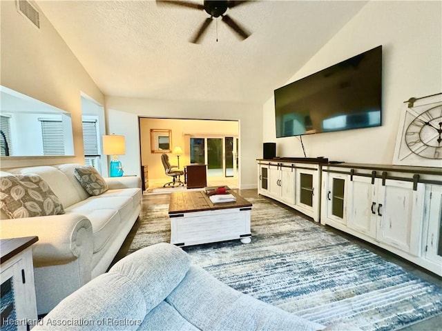 living room with ceiling fan, a textured ceiling, and vaulted ceiling