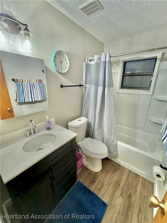 full bathroom with vanity, a textured ceiling, shower / tub combo with curtain, hardwood / wood-style floors, and toilet