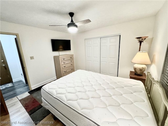 bedroom with hardwood / wood-style floors, ceiling fan, a textured ceiling, and a closet