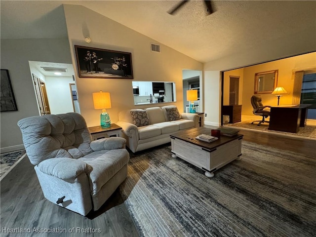 living room featuring dark hardwood / wood-style flooring, a textured ceiling, and vaulted ceiling