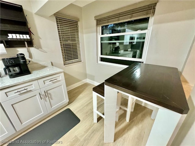 interior space with light stone countertops, white cabinetry, and light hardwood / wood-style flooring