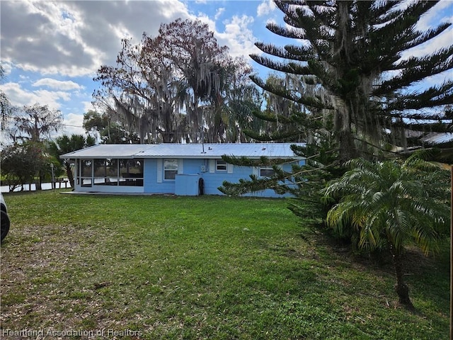 rear view of property featuring a sunroom and a lawn