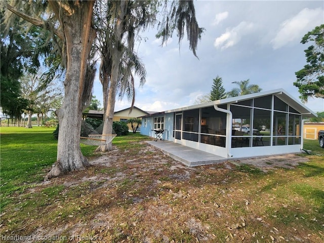 back of house featuring a lawn, a patio area, and a sunroom