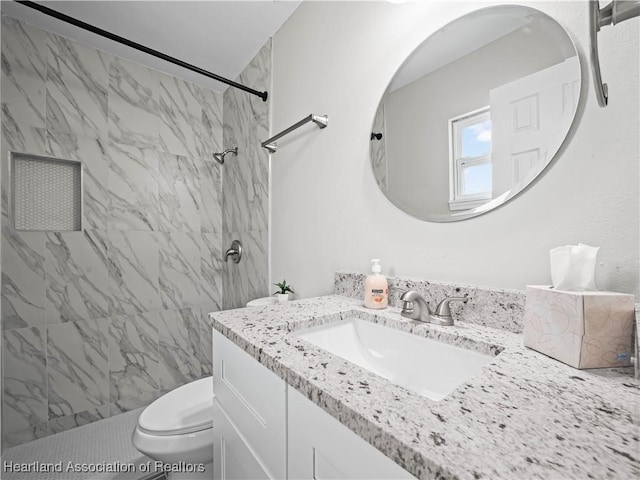 bathroom featuring vanity, tiled shower, and toilet