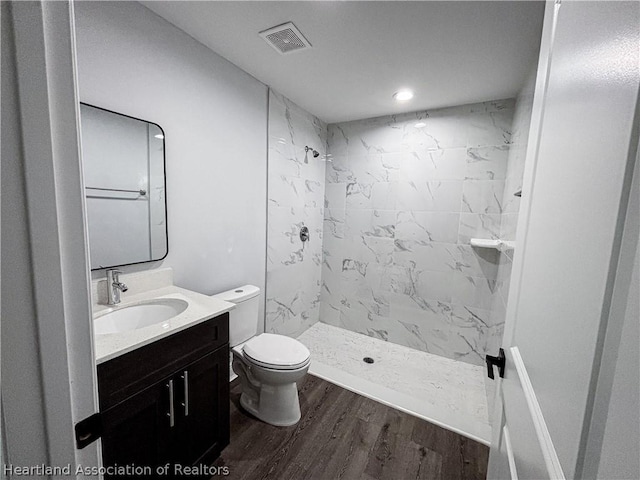 bathroom with hardwood / wood-style floors, vanity, toilet, and a shower