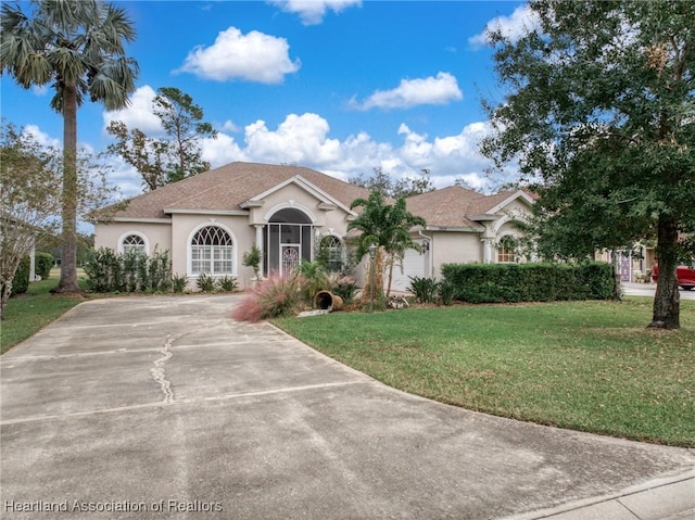 mediterranean / spanish home featuring a shingled roof, concrete driveway, a front lawn, and stucco siding