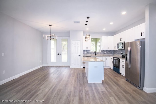 kitchen with hanging light fixtures, stainless steel appliances, a center island, and white cabinets